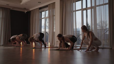 A-group-of-women-is-engaged-in-stretching-and-balance-with-an-instructor-in-a-beautiful-hall-with-large-windows.-Healthy-lifestyle-group-classes.-Women's-sports-club-slow-motion